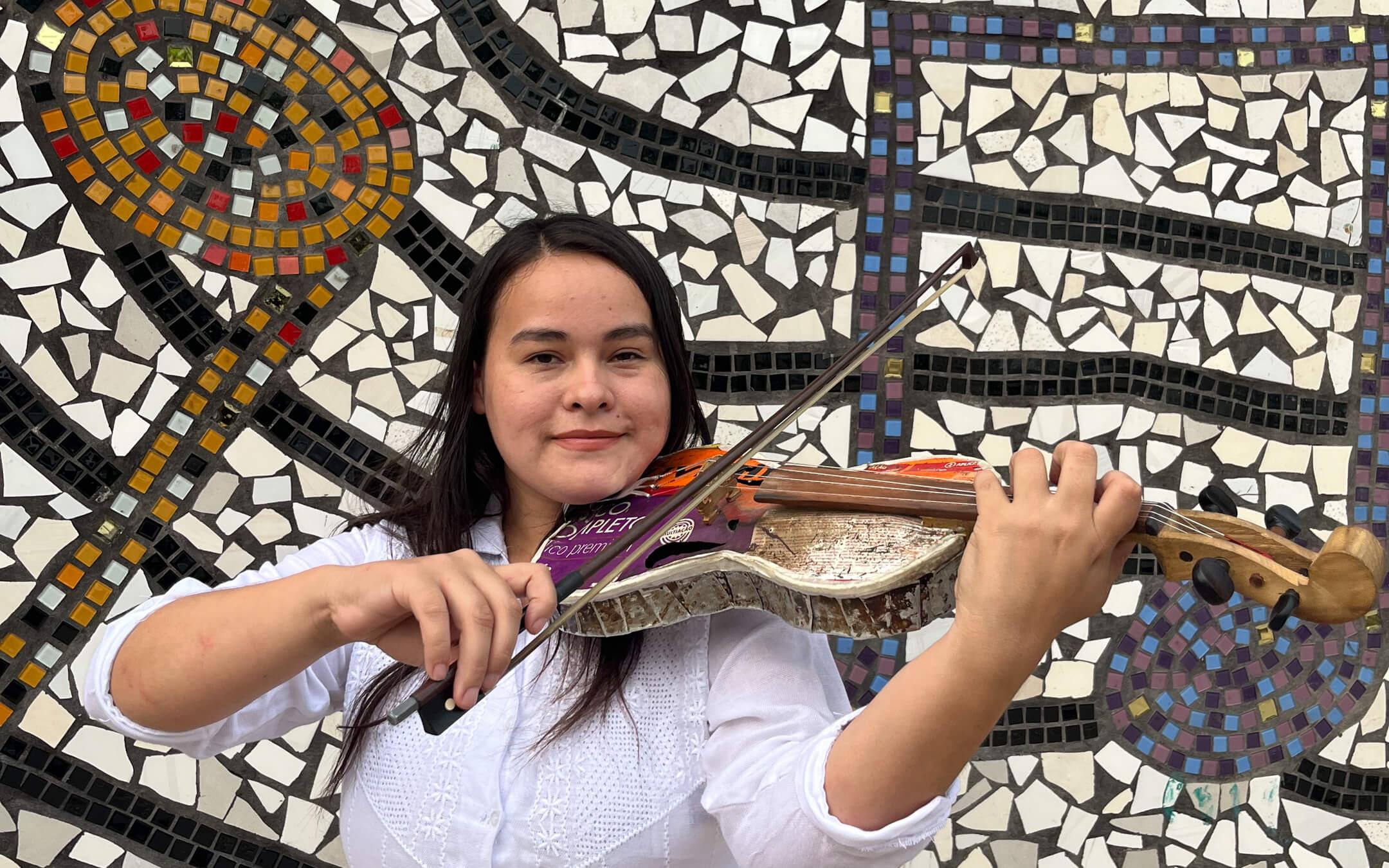 A member of the Recycled Orchestra of Cateura smiles for the camera as she plays on an upcycled violin.
Photo: Recycled Orchestra of Cateura