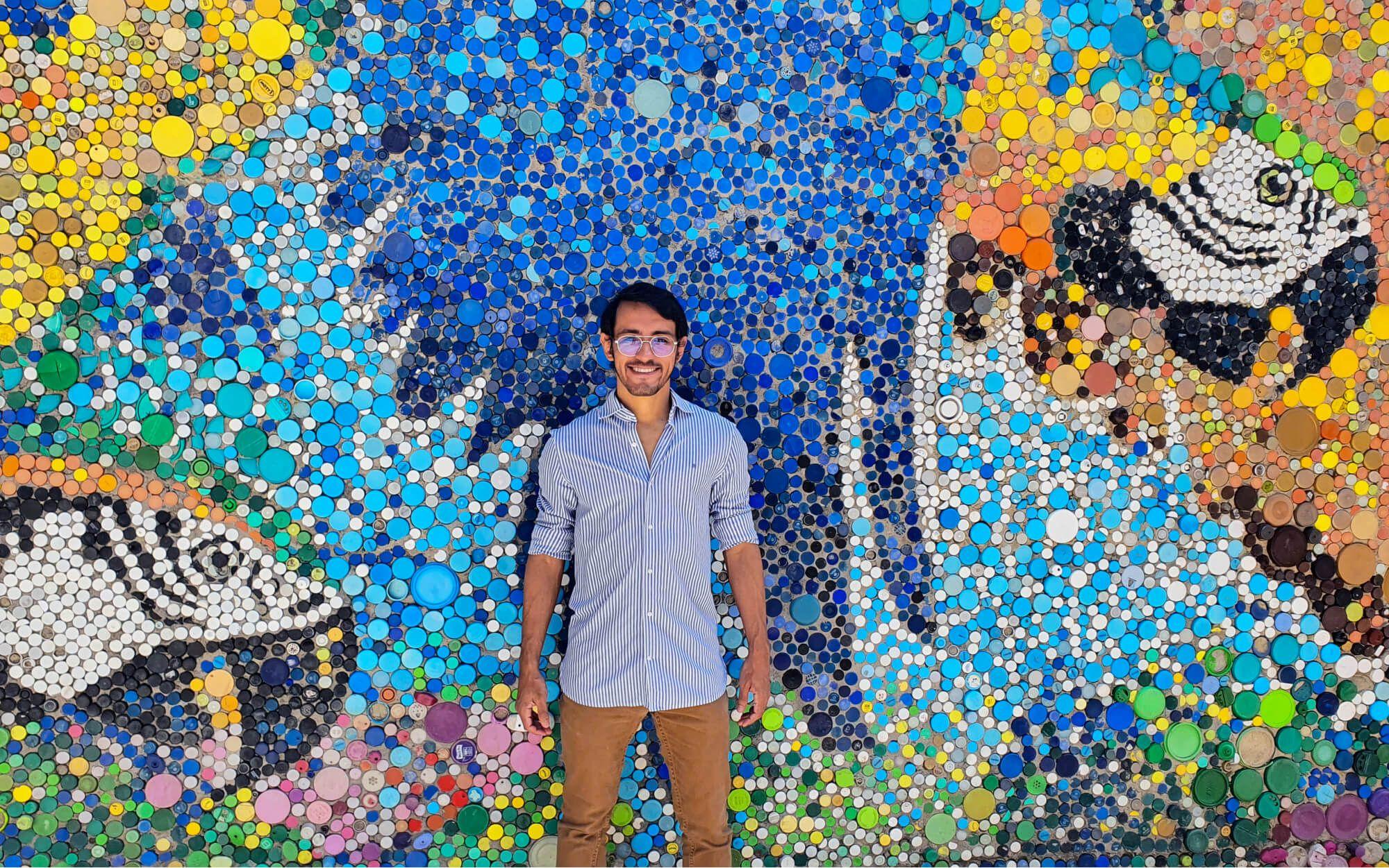 Oscar Olivares stands in front of a bottle cap mural.
Photo: Oscar Olivares