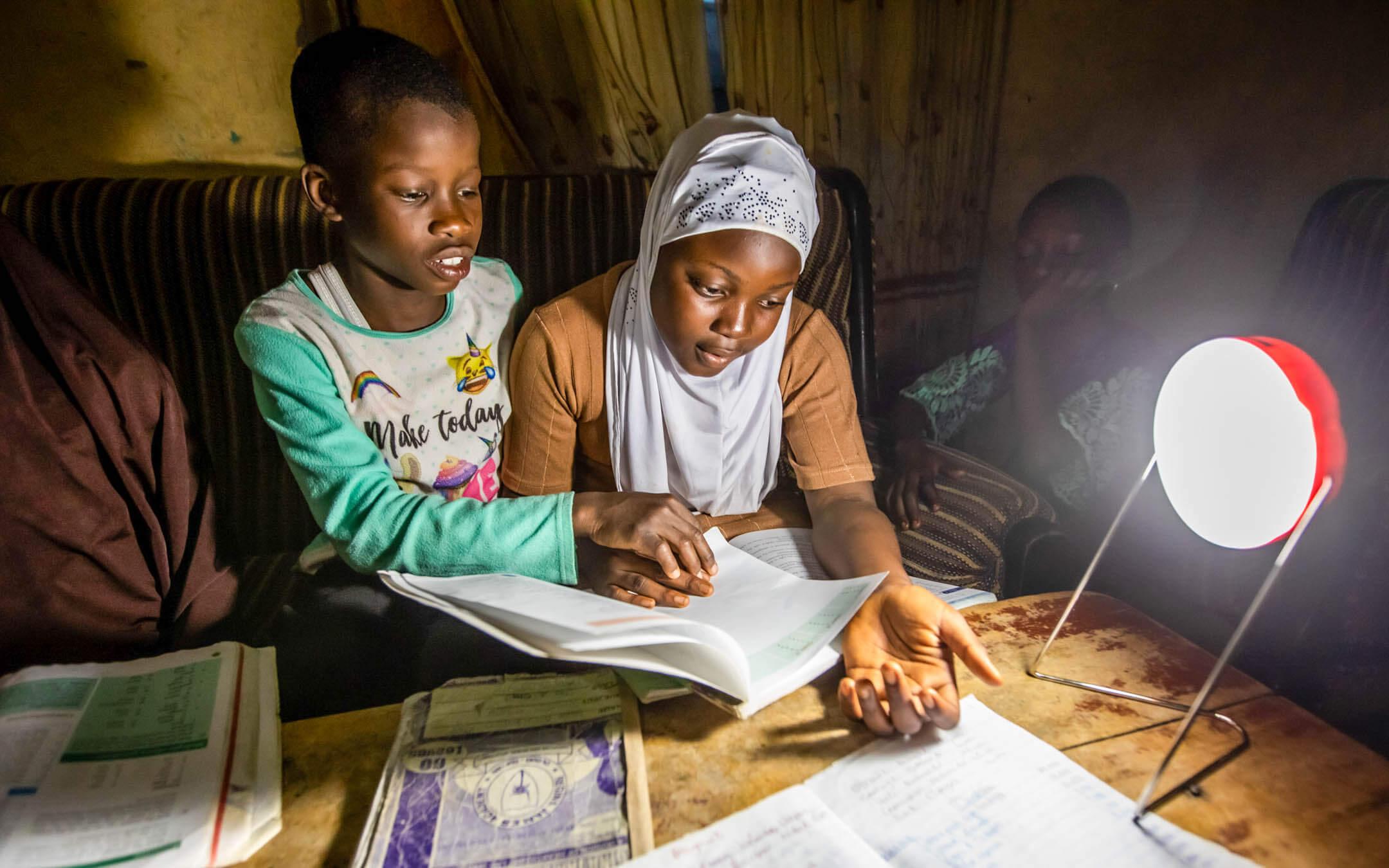 Young students complete their homework by the light of a solar lantern.
Photo: Solar Sisters